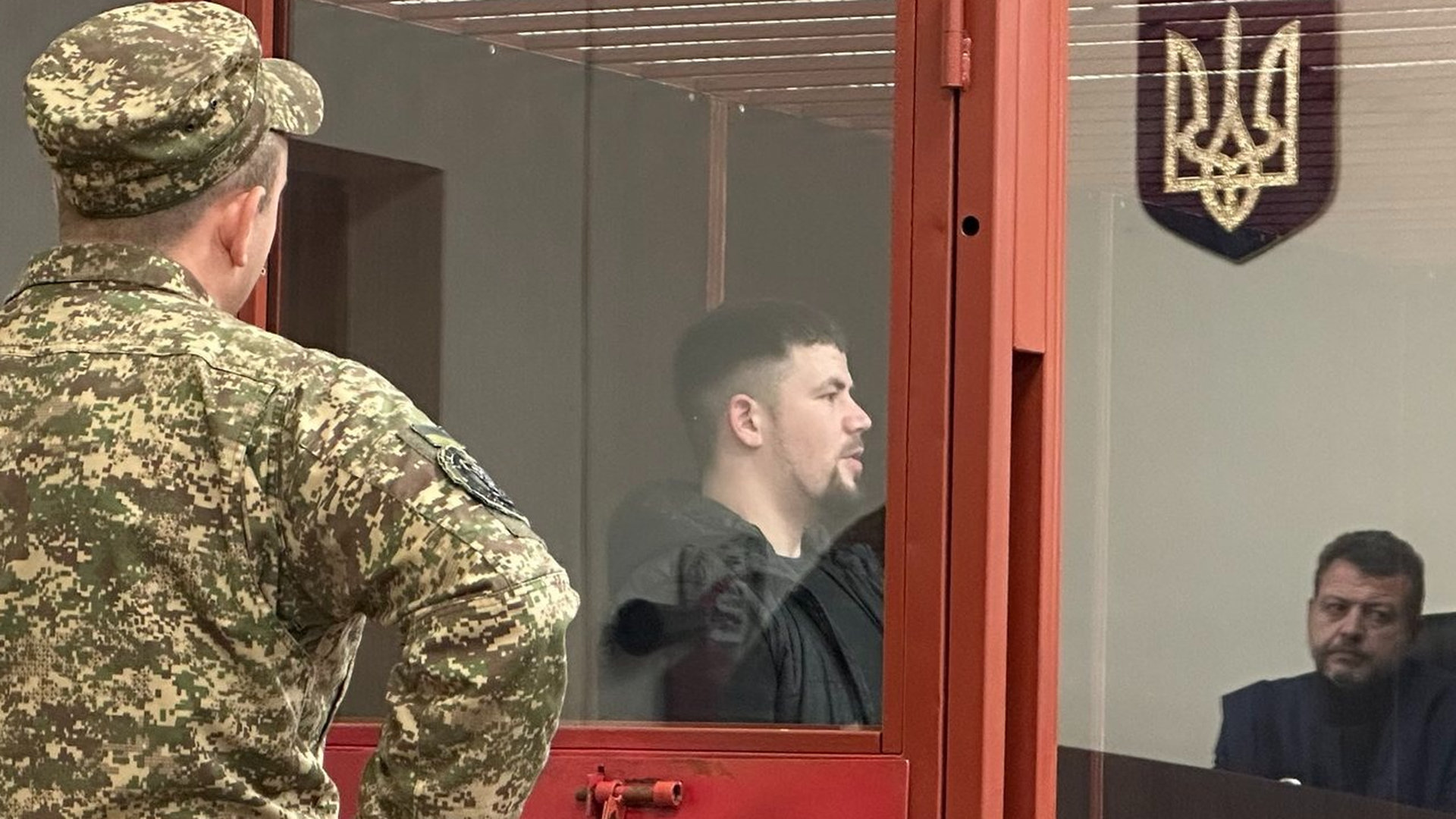 Підозрюваний Максим Бобилєв піл час судового засідання, а також видно суддю над головою якого висить герб України