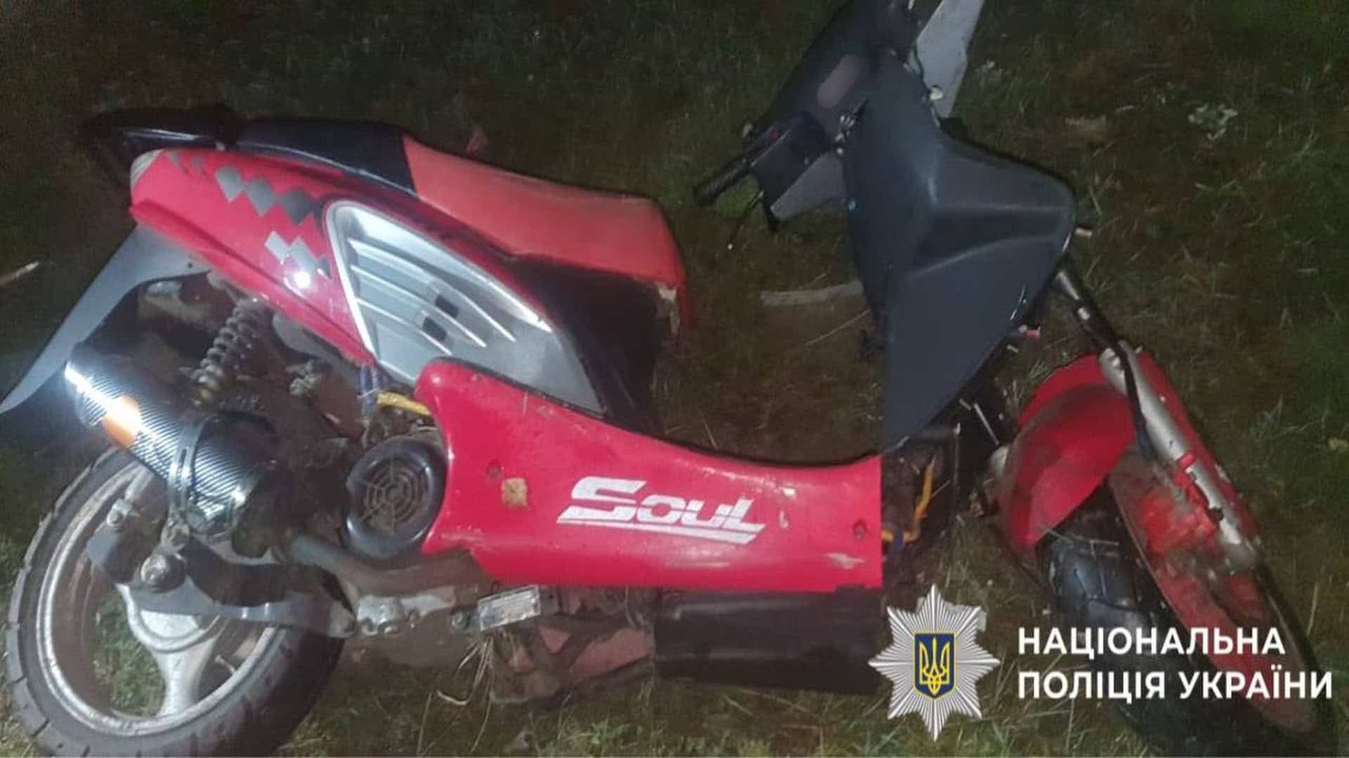 Червоний мотоскутер лежить на дорозі після ДТП