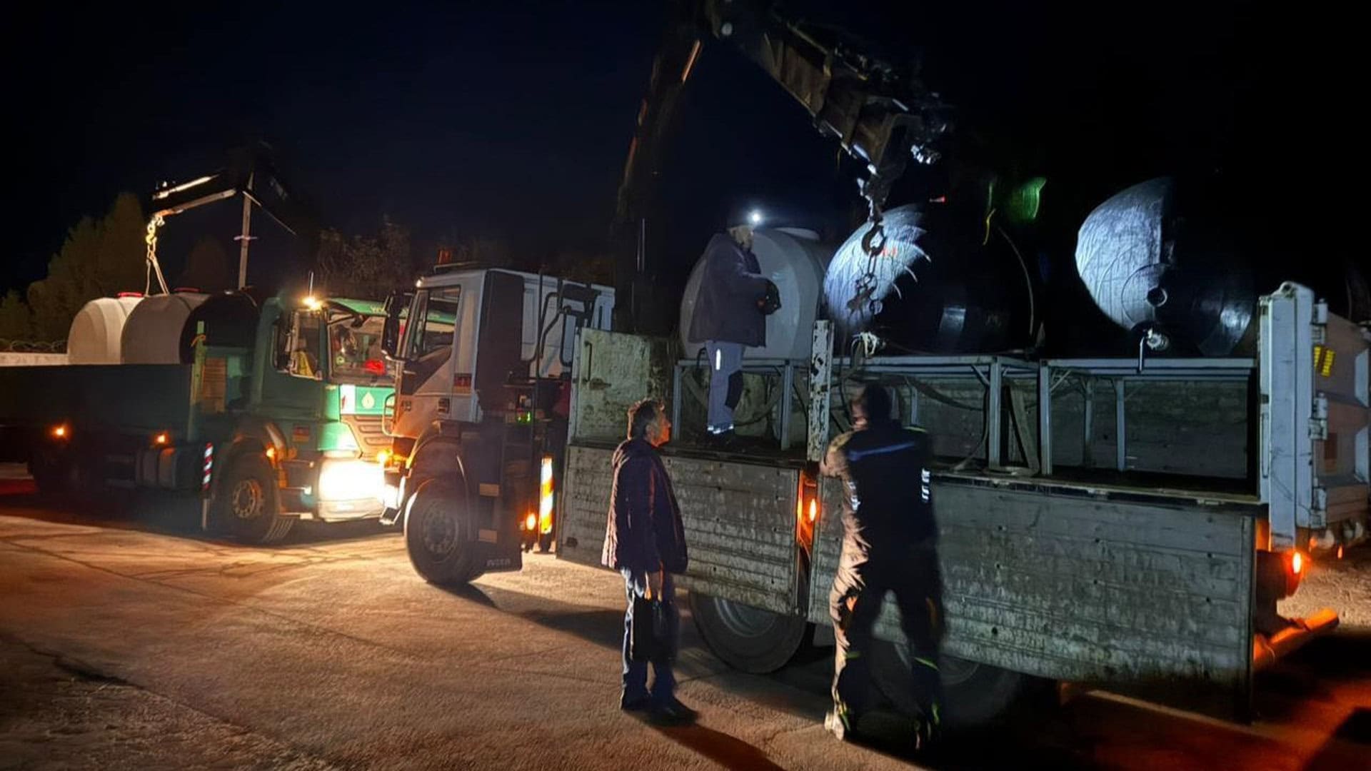 Нічне розвантаження великих металевих резервуарів краном з вантажівки для системи водопостачання Чернігова