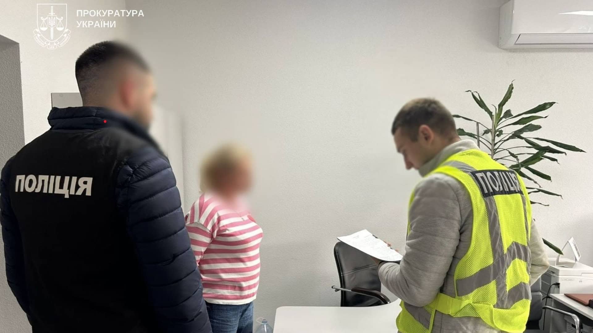 Двоє поліцейських говорять із жінкою в приміщенні якоїсь будівлі, схоже на кабінет державної установи