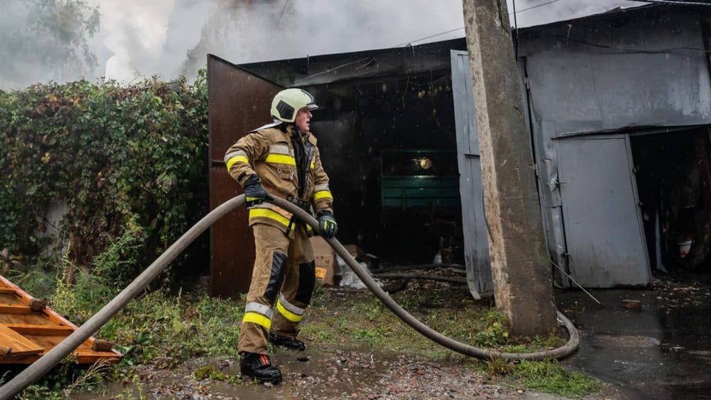 Пожежа на Саксаганського: рятувальники запобігли поширенню Пожежник стоїть зі шлангом біля гаража, який горить