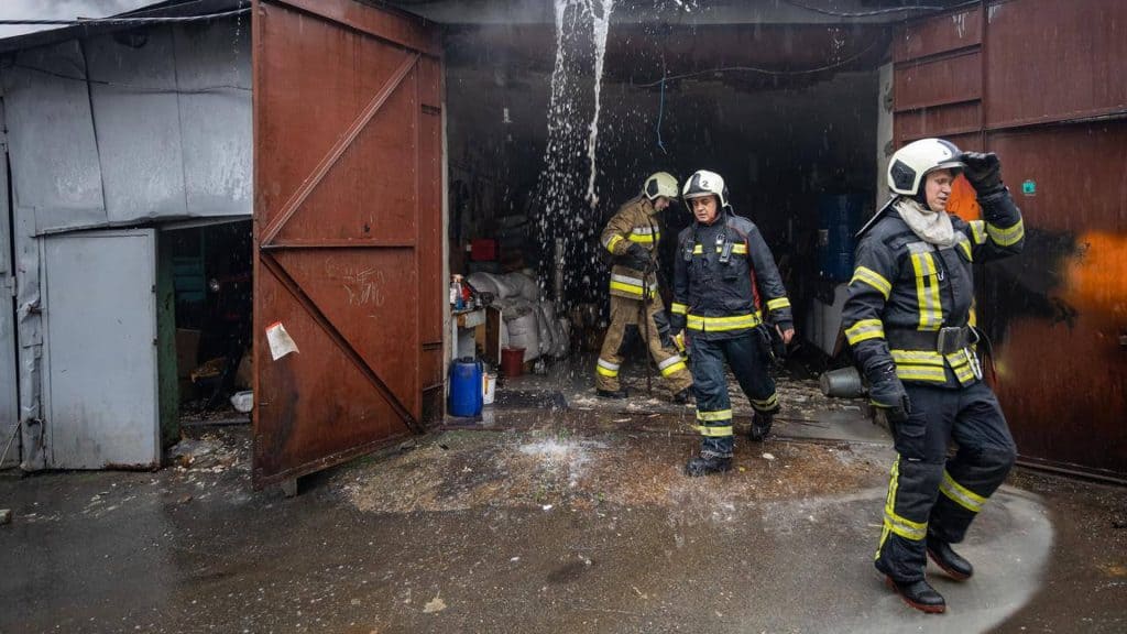Пожежа на Саксаганського: рятувальники запобігли поширенню Троє працівників ДСНС виходять з гаража, в якому була пожежа, вогонь загасили, зі стелі стікає вода