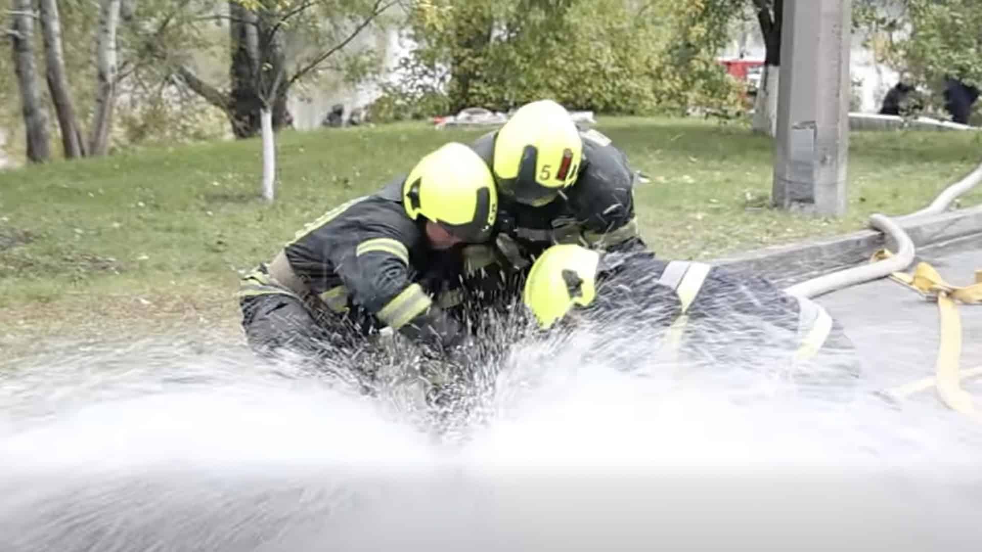 Троє рятувальників намагаються приборкати струмінь води
