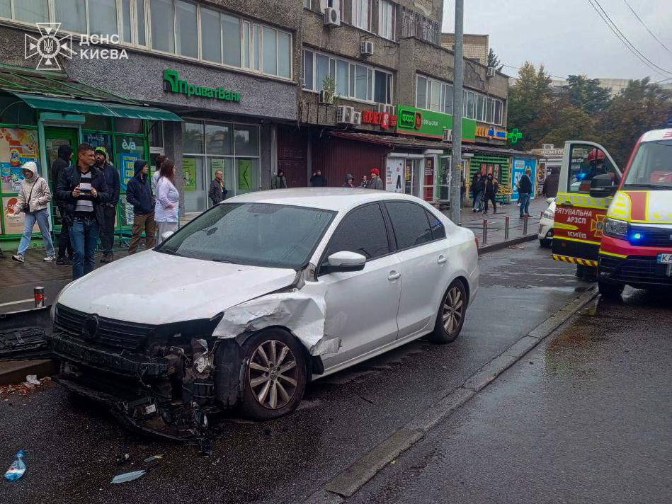 Білий седан із пошкодженим переднім бампером стоїть біля тротуару