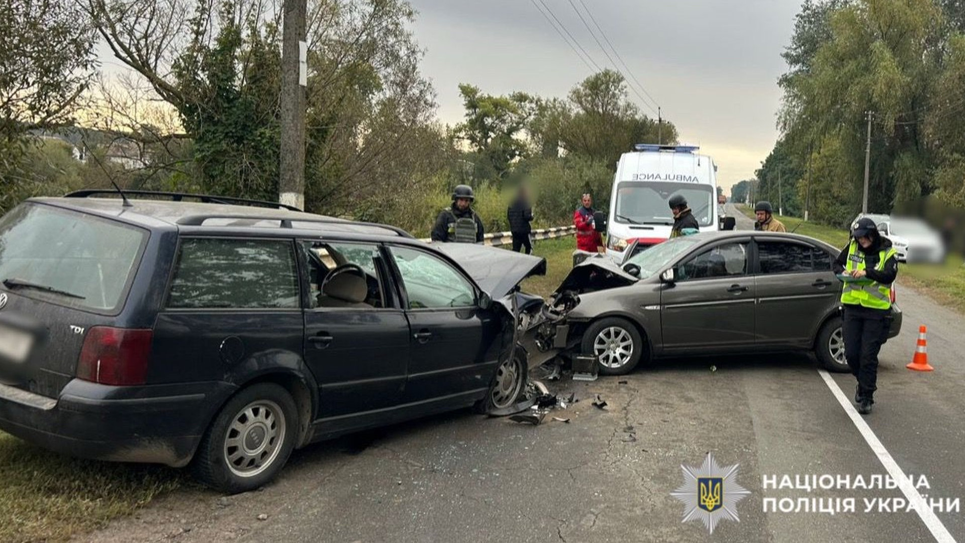 Автомобільна аварія, на фото два автомобіля, які зіштовхнулися і позаду них стоїть швидка допомога