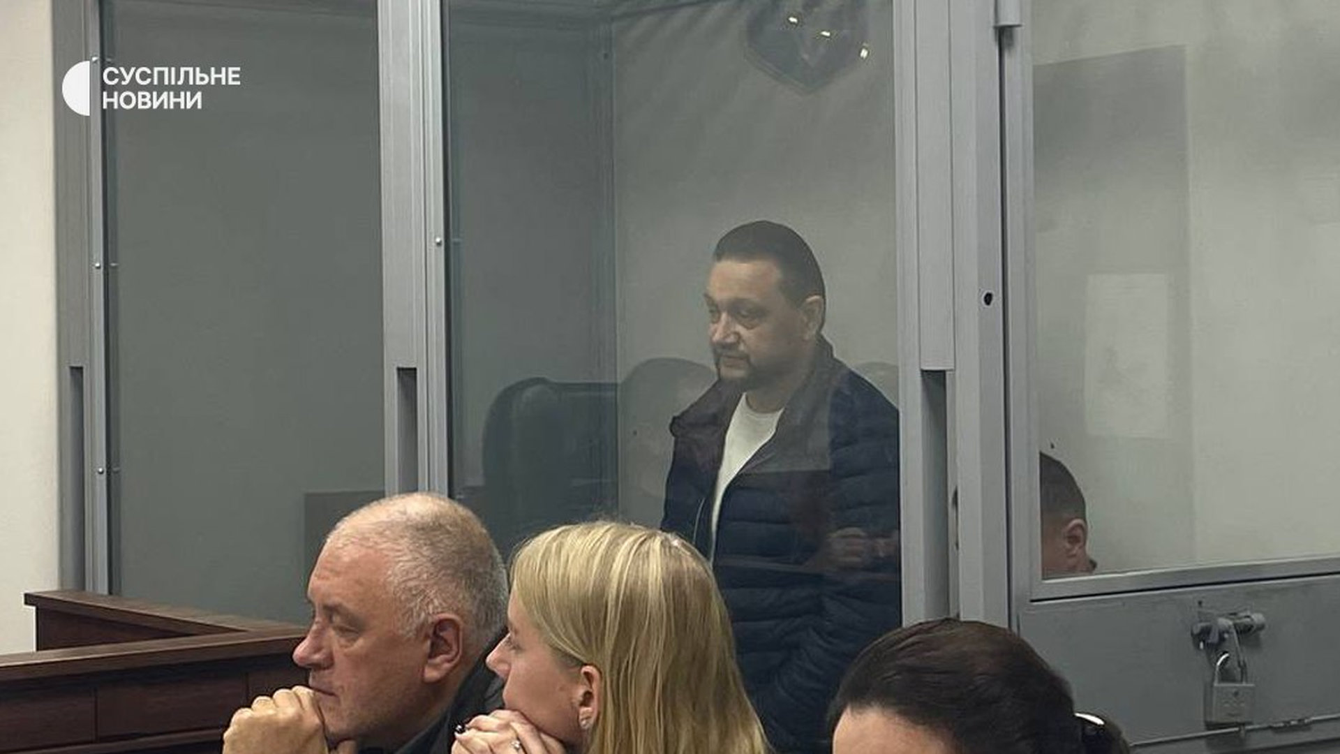 Судова зала, двоє підозрюваних у скляній камері