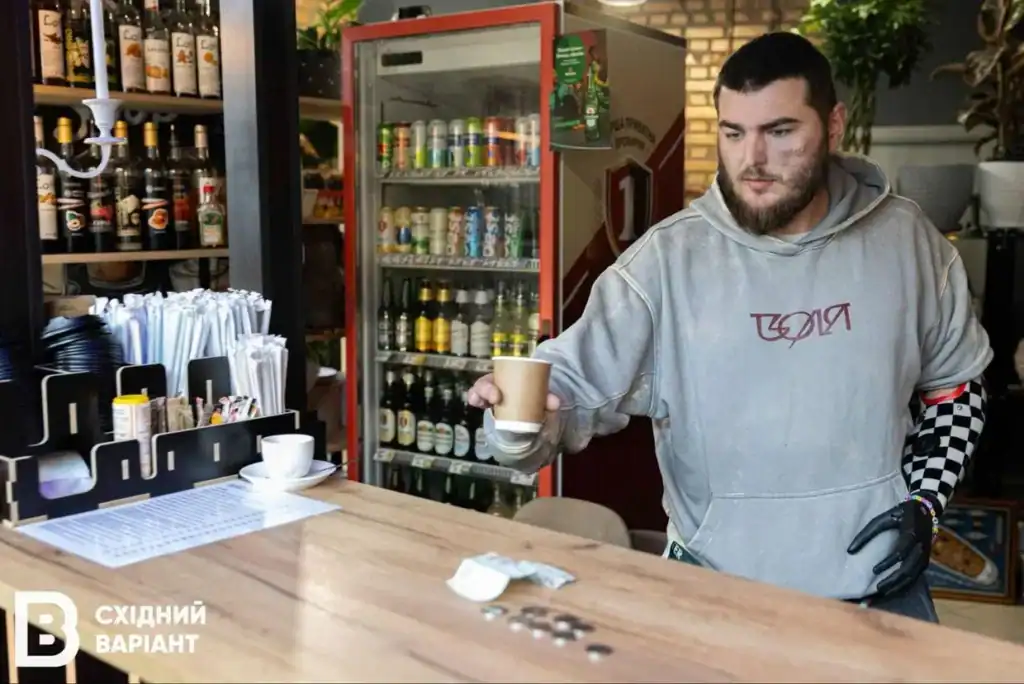 Ветеран із ампутацією в Ірпені дає стаканчик із кавою відвідувачу