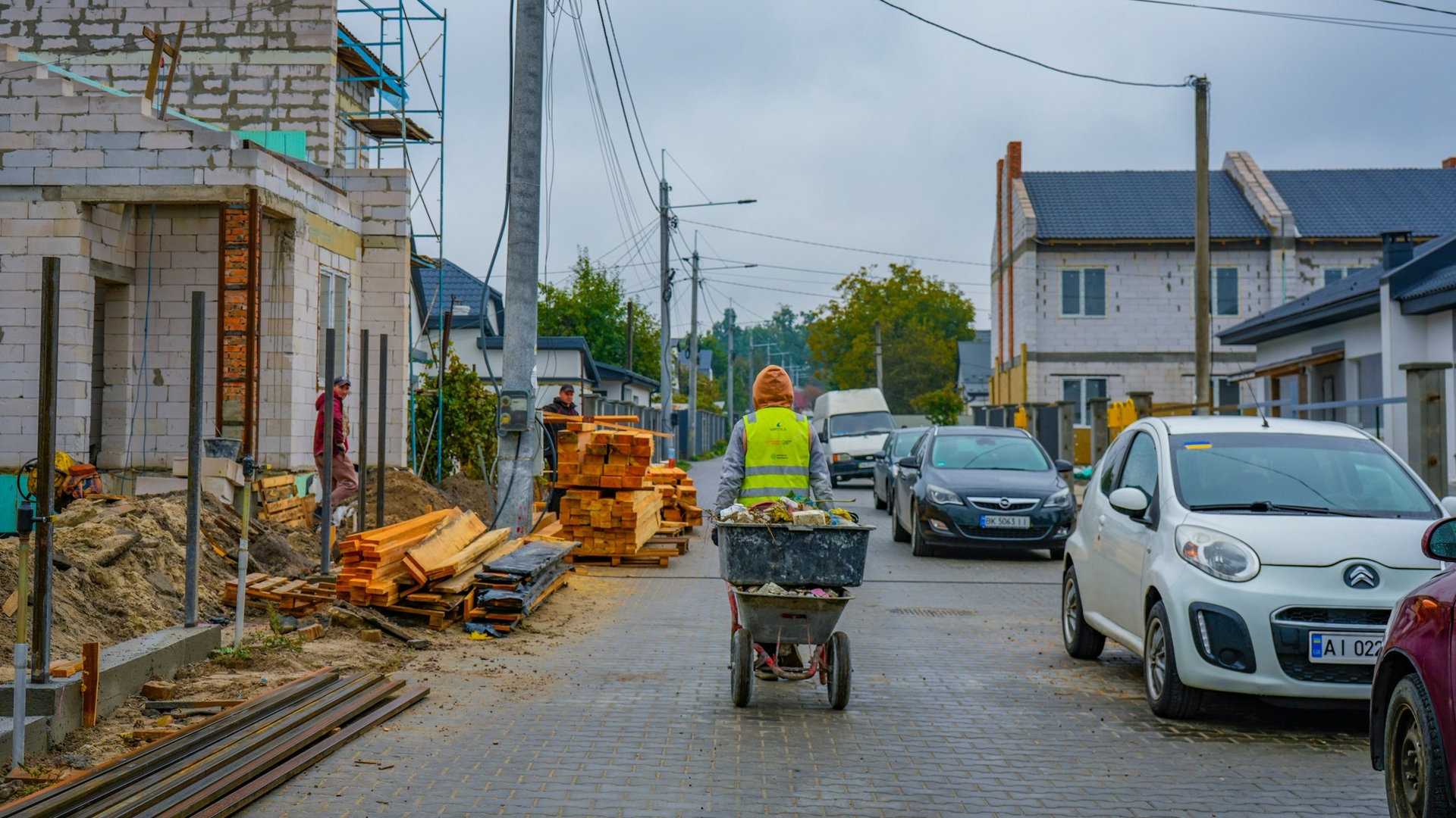 Ремонтні будівельні роботи на одній з вулиць Ірпеня, робітник на теліжці везе будівельне сміття