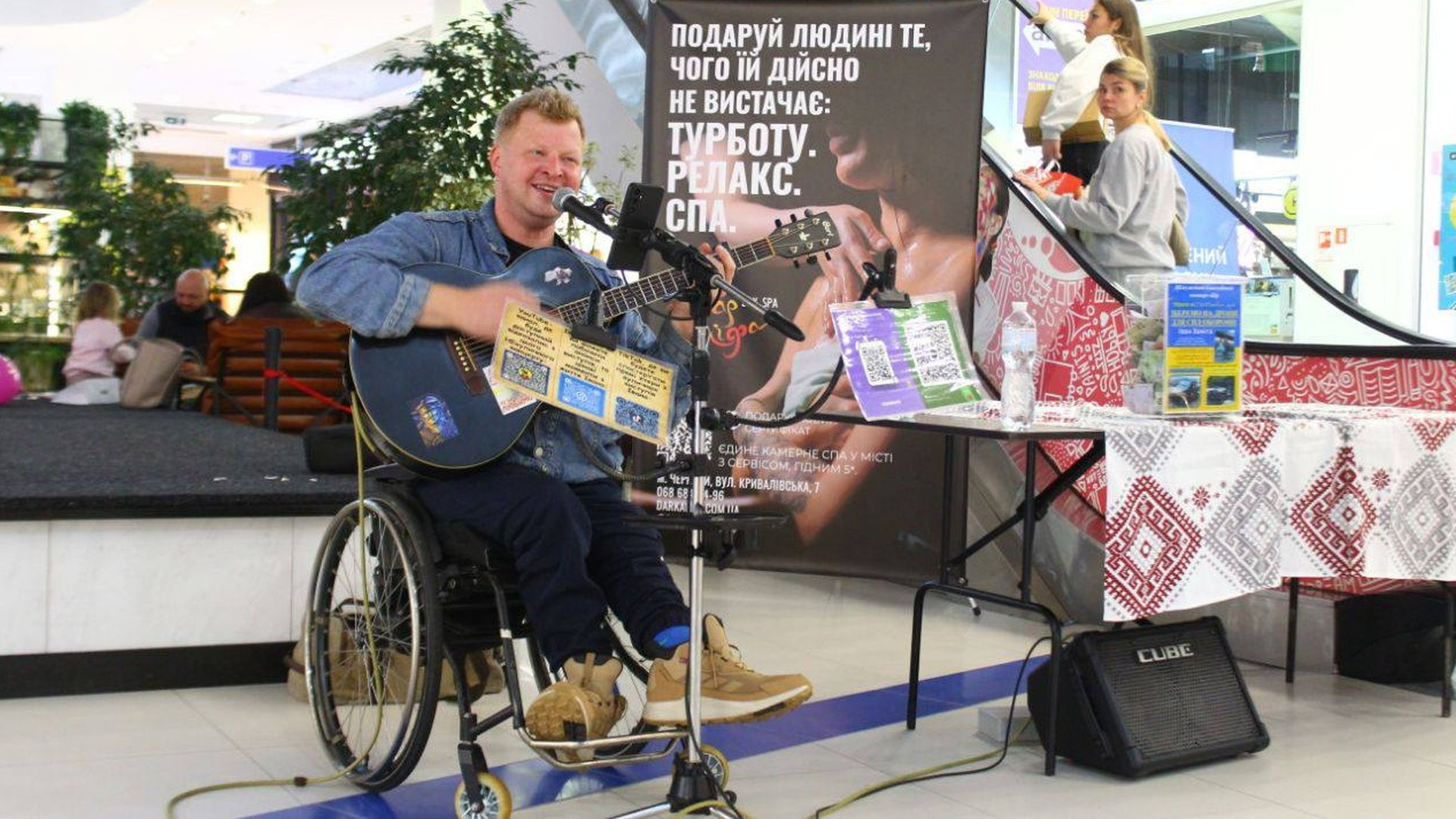 Іван Заміга на кріслі колісному співає в мікрофон і грає на гітарі