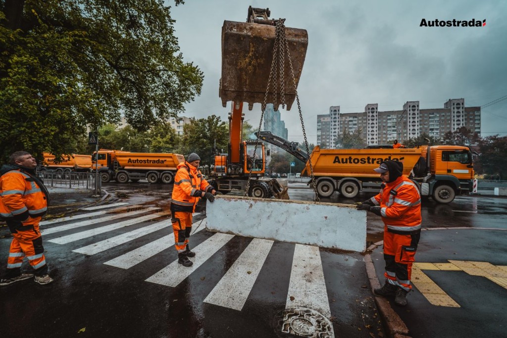Робітники у помаранчевих комбінезонах монтують дорожні блоки на пішохідному переході