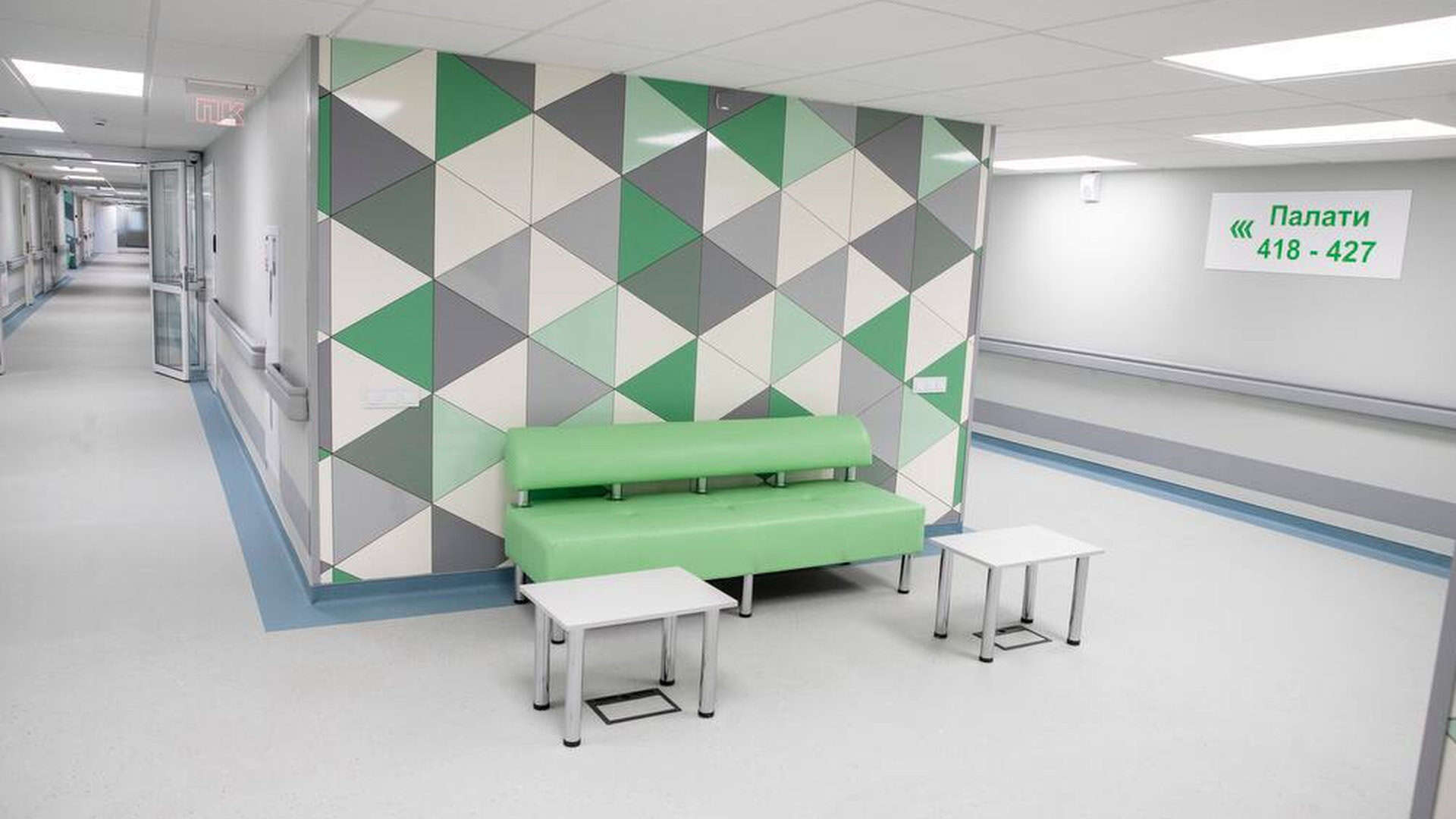 Нове відділення лікарні в зелено-сірому стилі, посеред коридору салатовий диван і два білих столика
