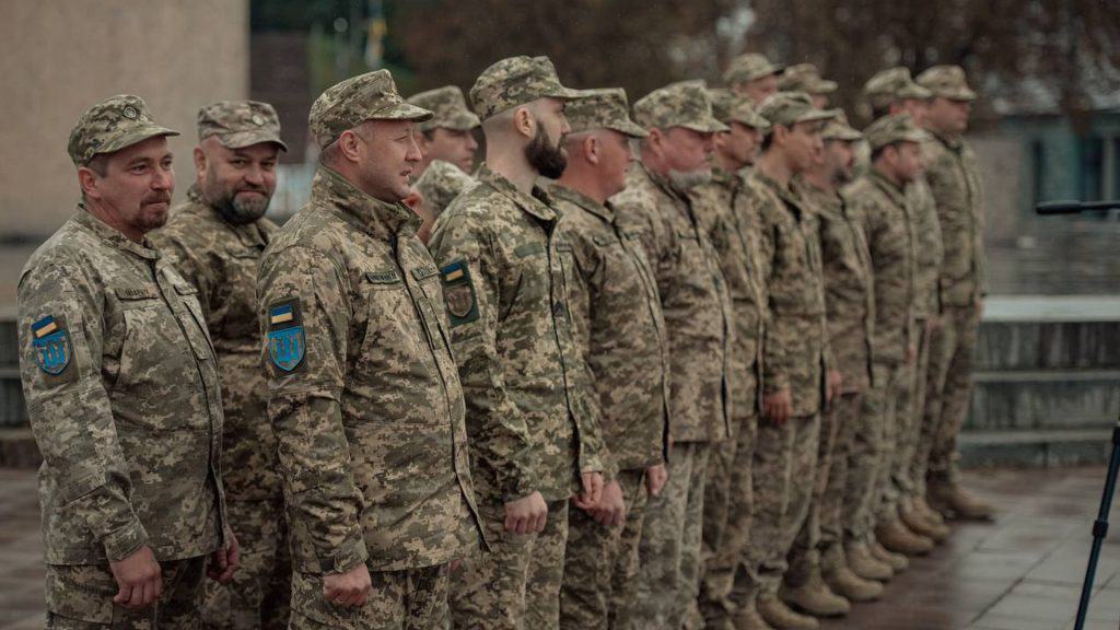 Київ: на Алеї Захисників відкрили пам’ятний знак воїнам ТРО України Пʼятнадцять військових у військовій формі стоять в ряд на плацу, всі вони бійці ТРО