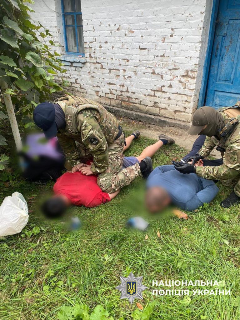 Двоє чоловіків у цивільному лежать обличчям донизу на траві, їх затримують спецпризначенці біля будинку