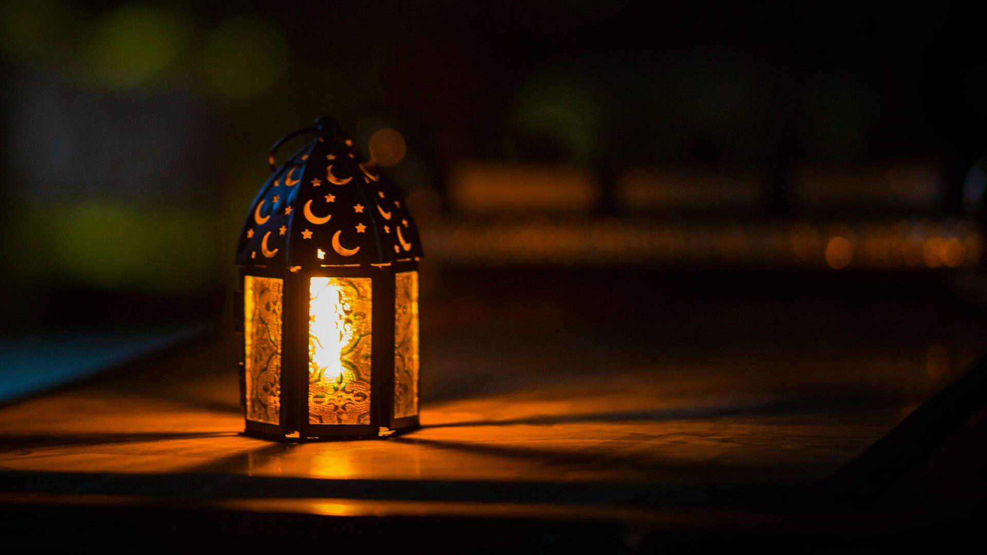 Невеличка лампадка зі свічкою стоїть на столі у темряві