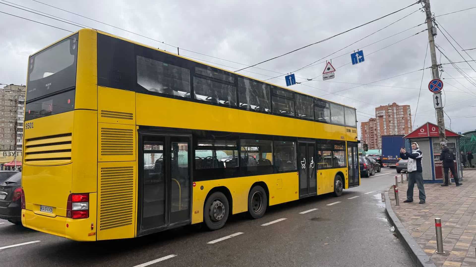 Двоповерховий автобус виїжджає з зупинки на міській вулиці