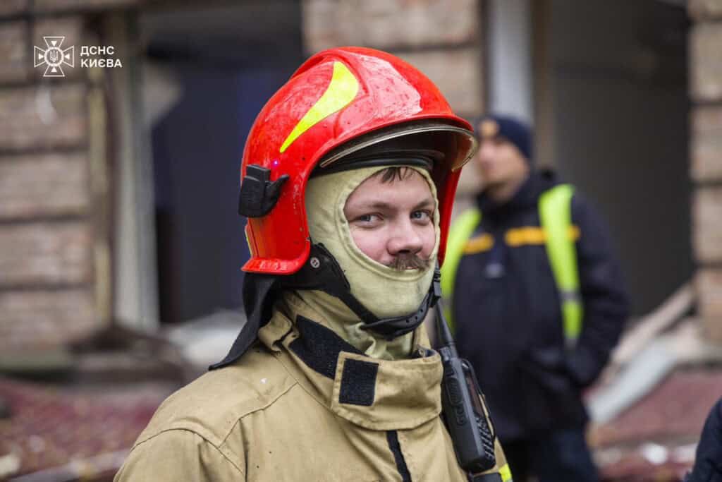 «Подивіться у ці обличчя»: ДСНС показала портрети тих, хто рятує Київ Портрет рятувальника в червоному шоломі і в балаклаві бежевого кольору, рот його закритий, але видно по очах, що він посміхається