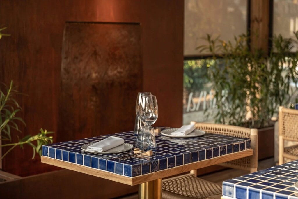 Столик з синьою мозаїчною стільницею та плетеними кріслами