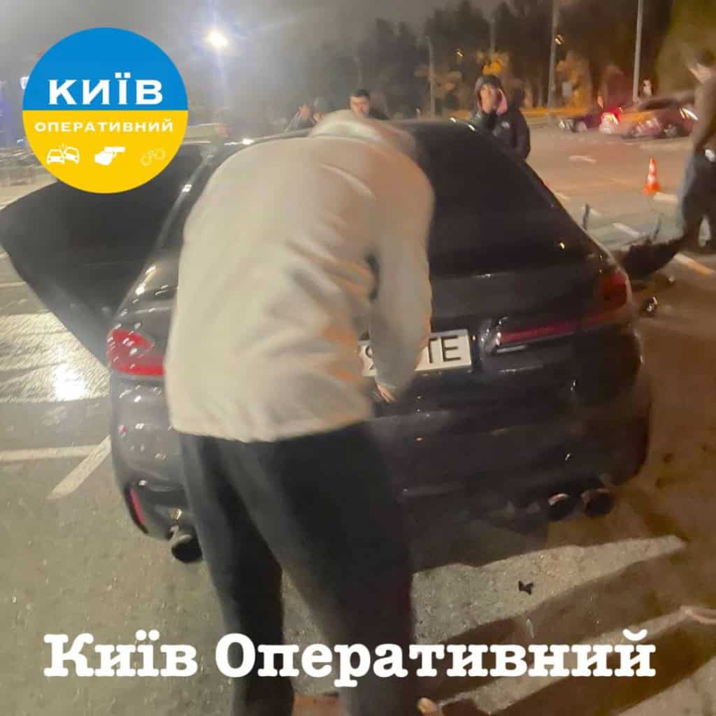 На паркінгу Lavina Mall дрифтери розтрощили чотири авто: є постраждалі (фото) Чоловік у світлій куртці нахиляється над багажником чорного авто
