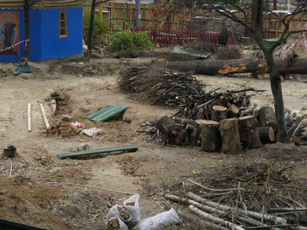 Попи Московського патріархату захопили сквер поруч зі штабом Сухопутних військ (фото) Місце після вирубки дерев із купами пнів, гілок та синьою будівлею на тлі