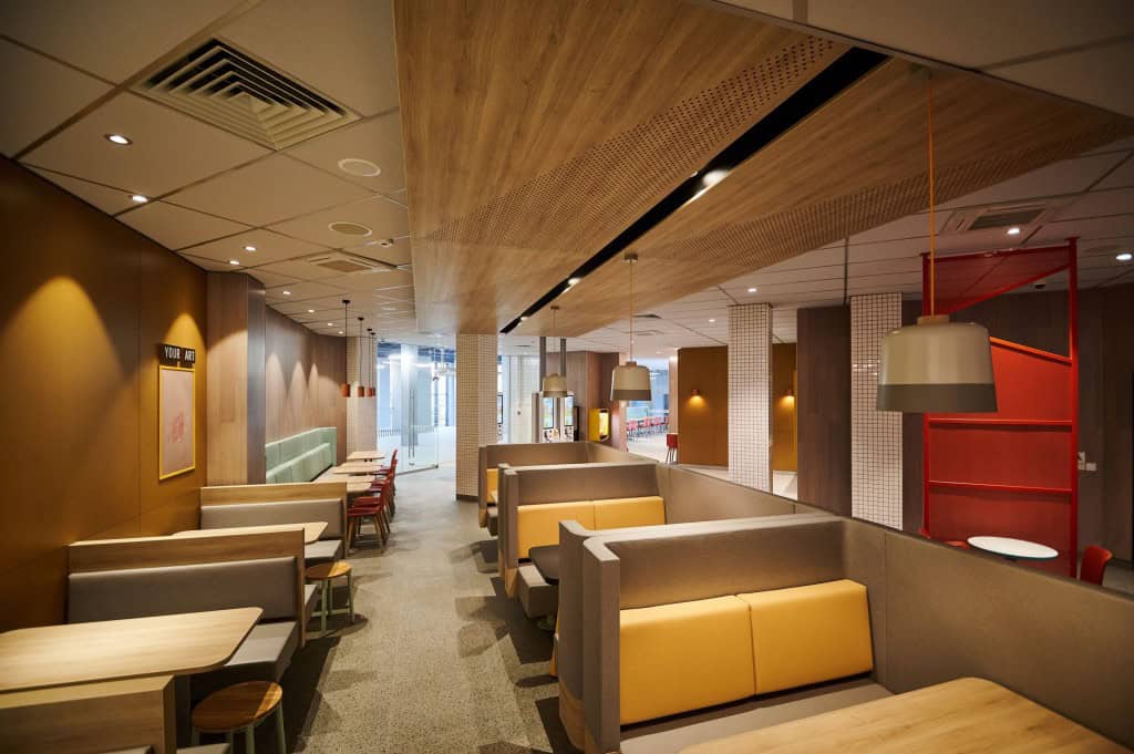 Інтер’єр ресторану — дерев’яні столи, жовті дивани й сучасне освітлення