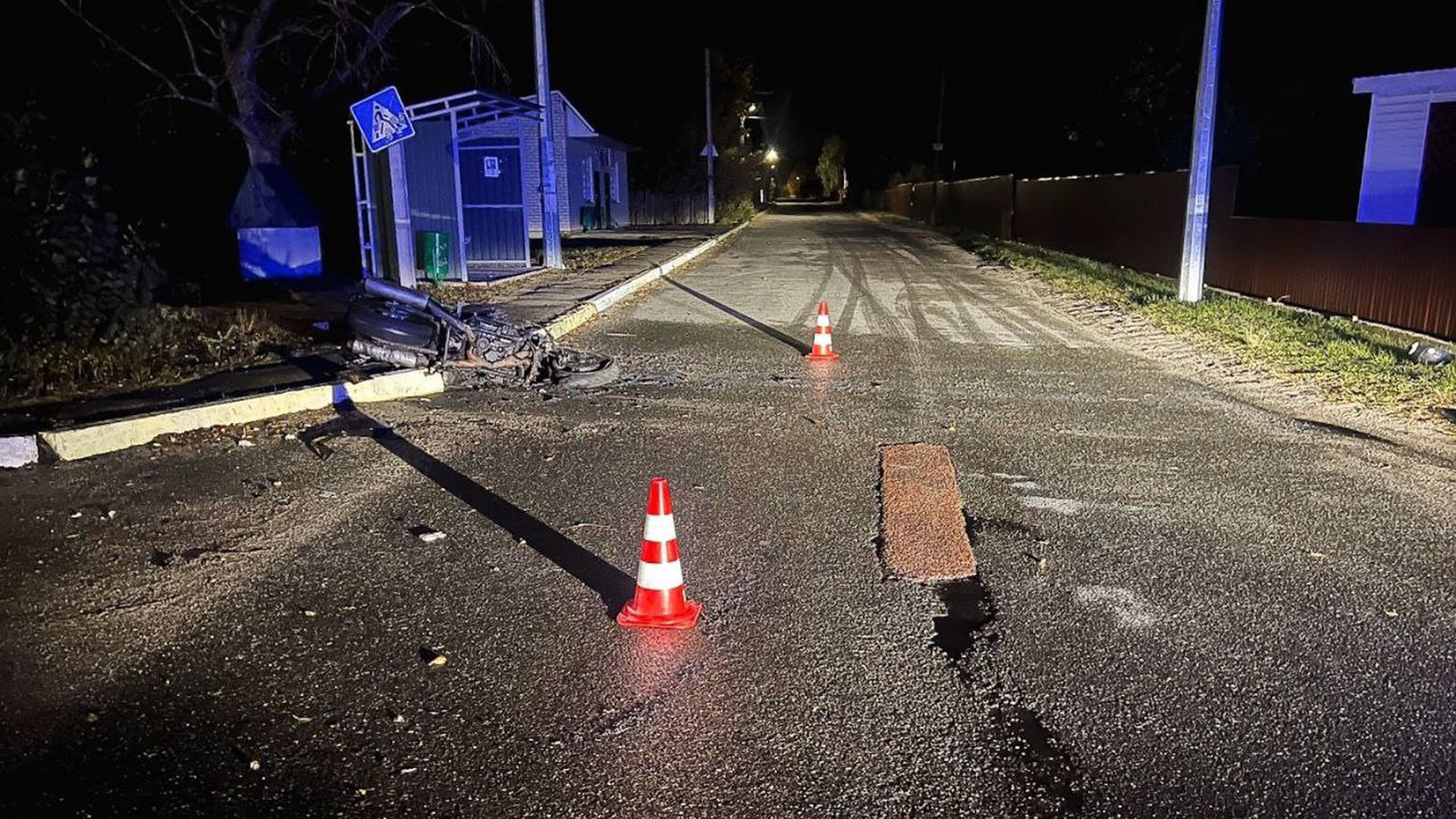 Темна дорога і мотоцикл який лежить на дорозі після ДТП