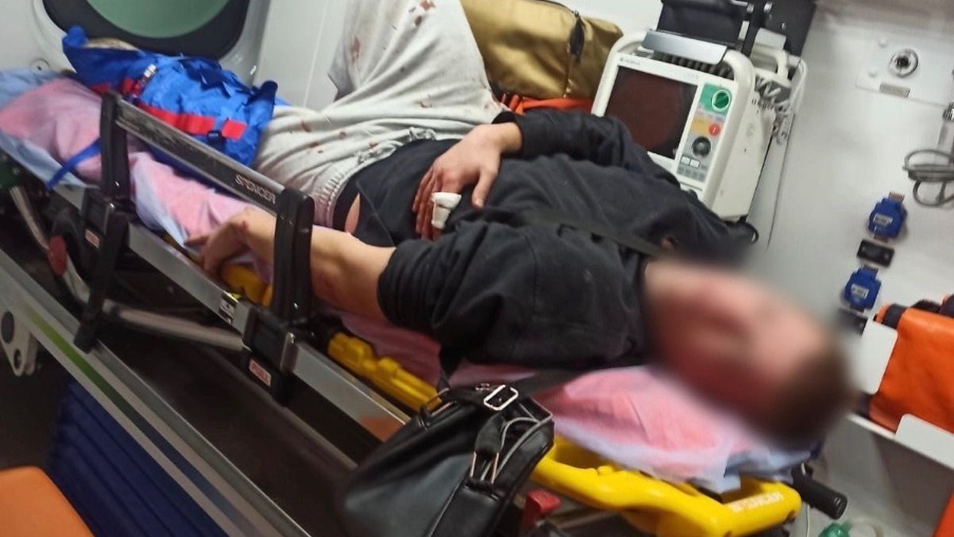 Чоловік лежить на ношах у кареті швидкої допомоги, обличчя заблюрене