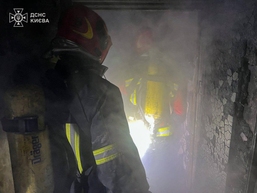 Рятувальники у захисному спорядженні працюють у задимленому приміщенні після пожежі