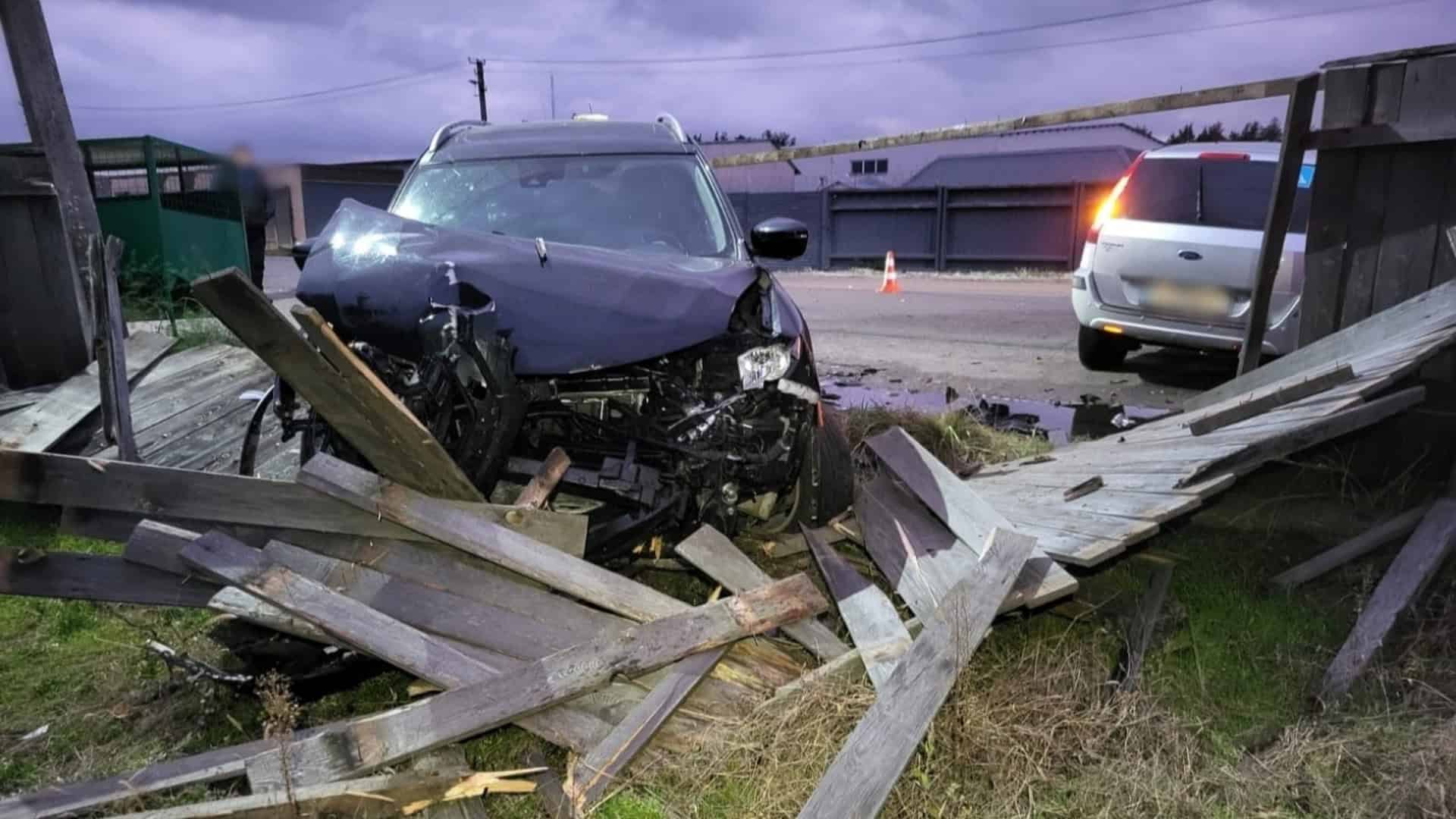 Автомобіль Nissan з розбитим капотом стоїть на узбіччі біля поваленого деревʼяного паркану