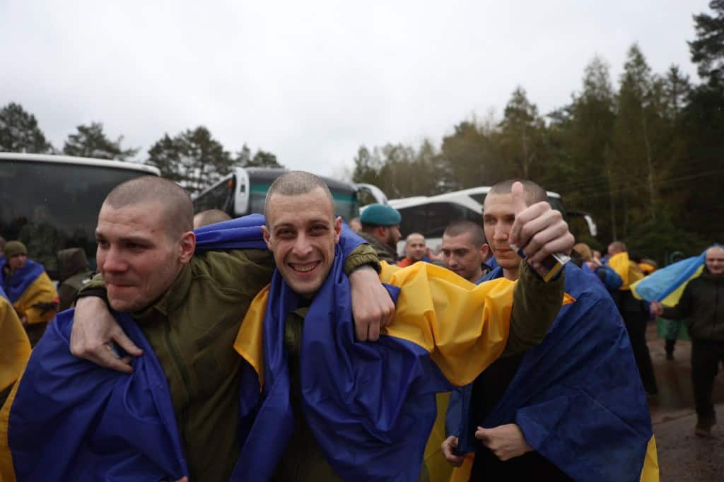 Україна визволила з полону РФ 205 людей: 185 оборонців та 20 цивільних (фото) Українські військовополонених після повернення з російського полону — чоловіки з усмішками, обгорнуті державними прапорами