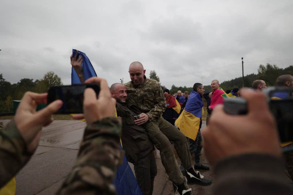 Україна визволила з полону РФ 205 людей: 185 оборонців та 20 цивільних (фото) Українські військовополонених після повернення з російського полону — чоловіки з усмішками, обгорнуті державними прапорами