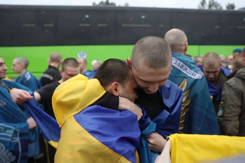 Україна визволила з полону РФ 205 людей: 185 оборонців та 20 цивільних (фото) Українські військовополонених після повернення з російського полону — чоловіки з усмішками, обгорнуті державними прапорами