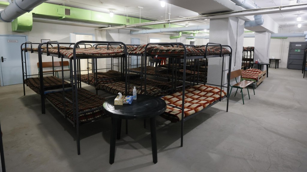 Велике підземне приміщення з рядами металевих двоярусних ліжок у клітинку