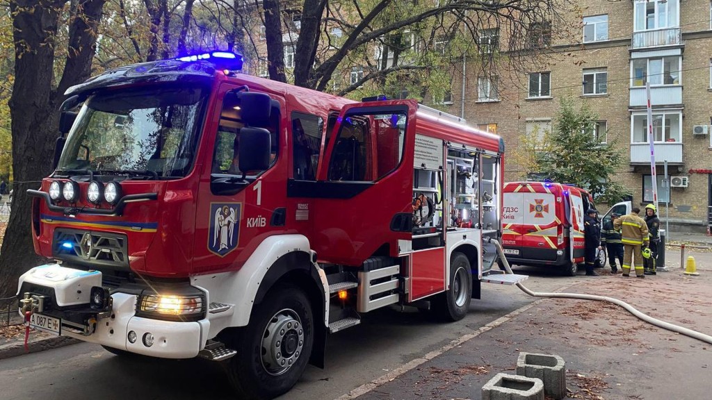 Дві червоні машини ДСНС у дворі багатоповерхівки Києва разом із рятувальниками