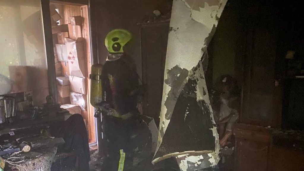 Пожежник в квартирі де сталася пожежа, стіни обгорілі, все навколо чорне