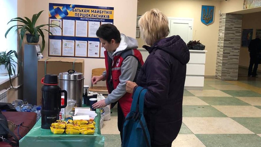 В Пункті незламності волонтер робить гарячий чай для відвідувачки, житло якої постраждало від атаки росіян житлового будинку
