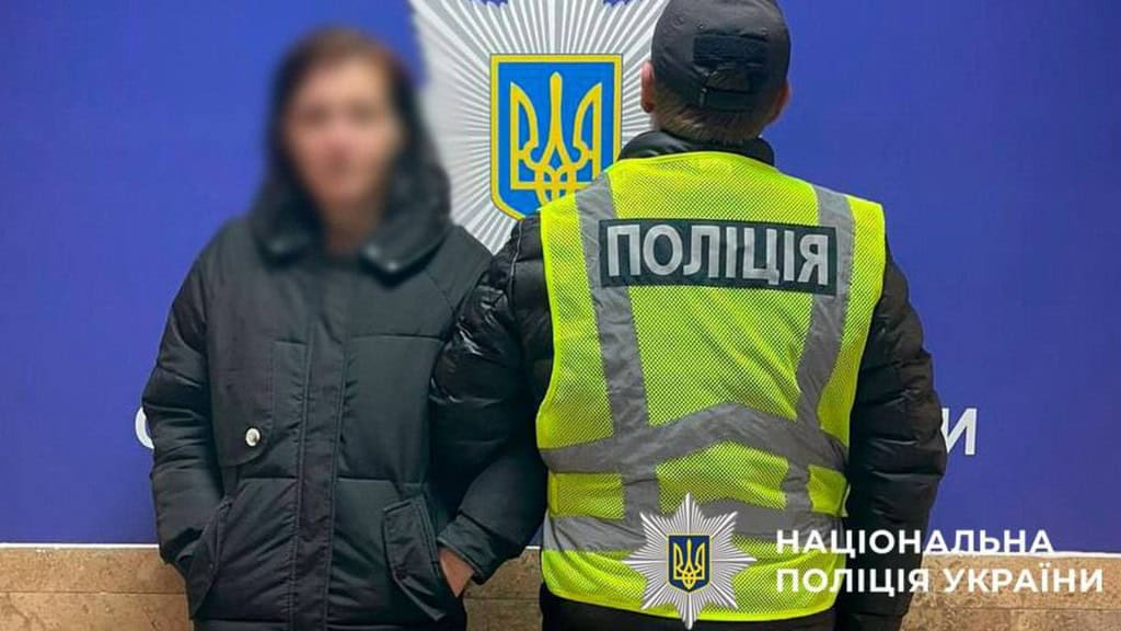 У Києві жінка викинула цуценя з вікна: поліція веде справу Працівник поліції тримає під руку жінку, яку підозрюють у вбивстві собаки