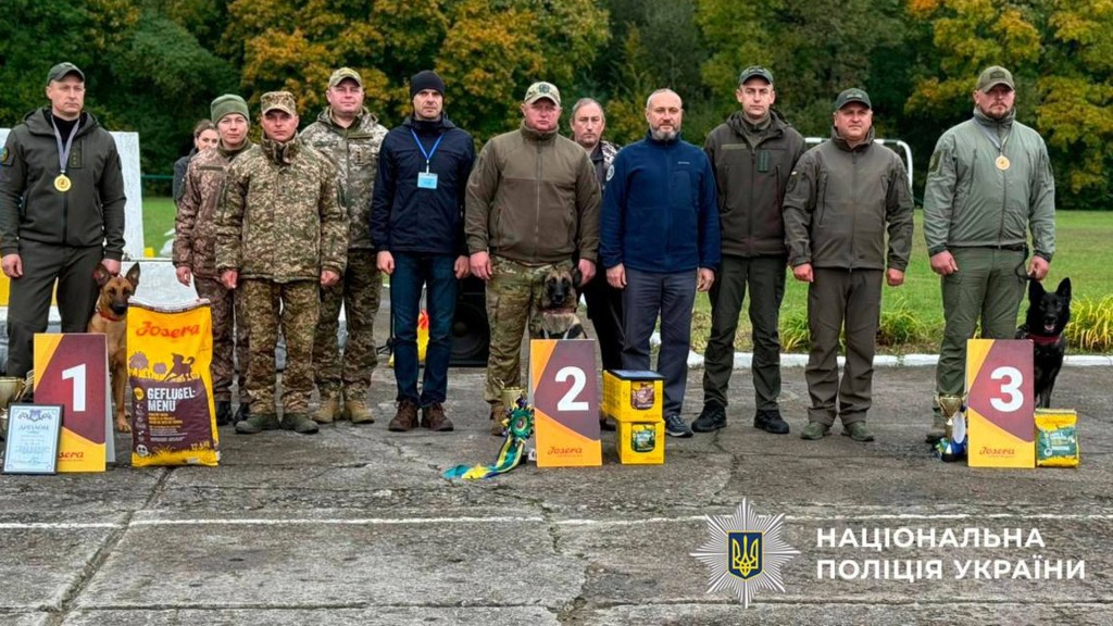 Три пси переможця і багато людей в формі правоохоронців біля них