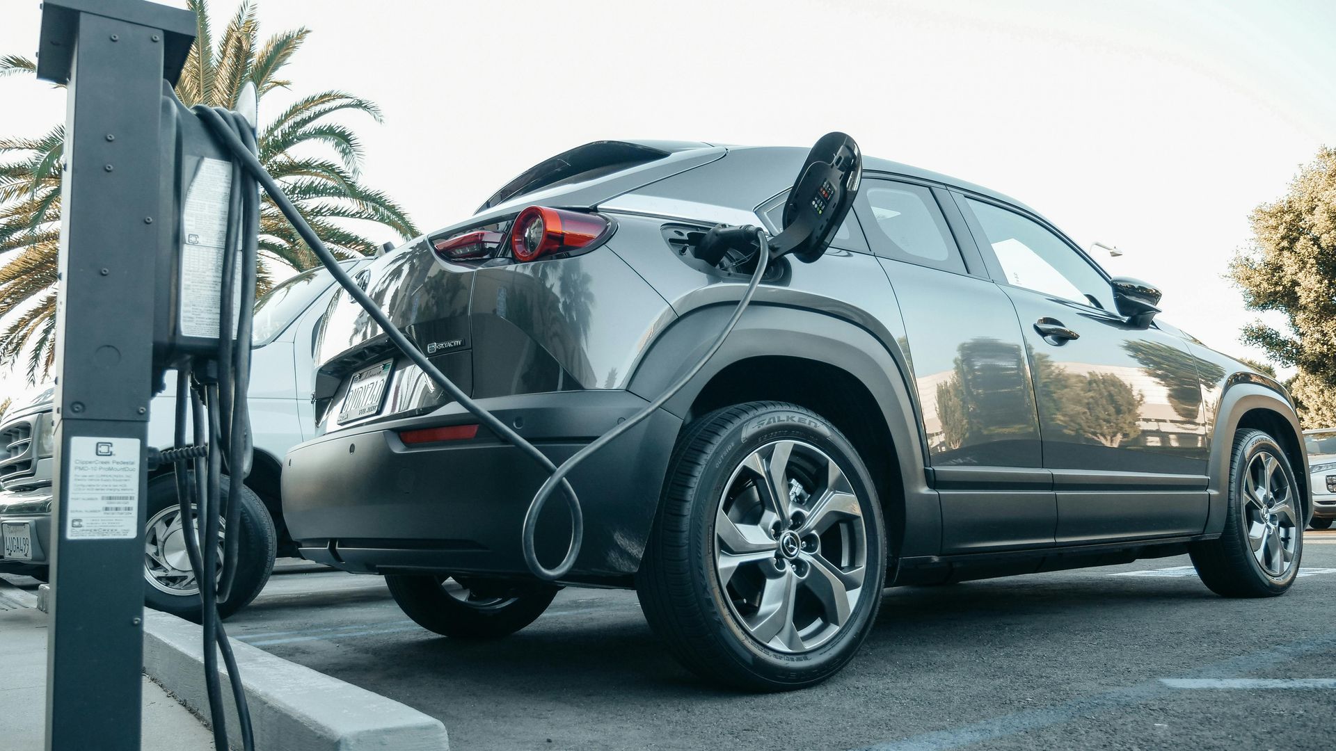 Сірий електромобіль, припаркований на зарядній станції