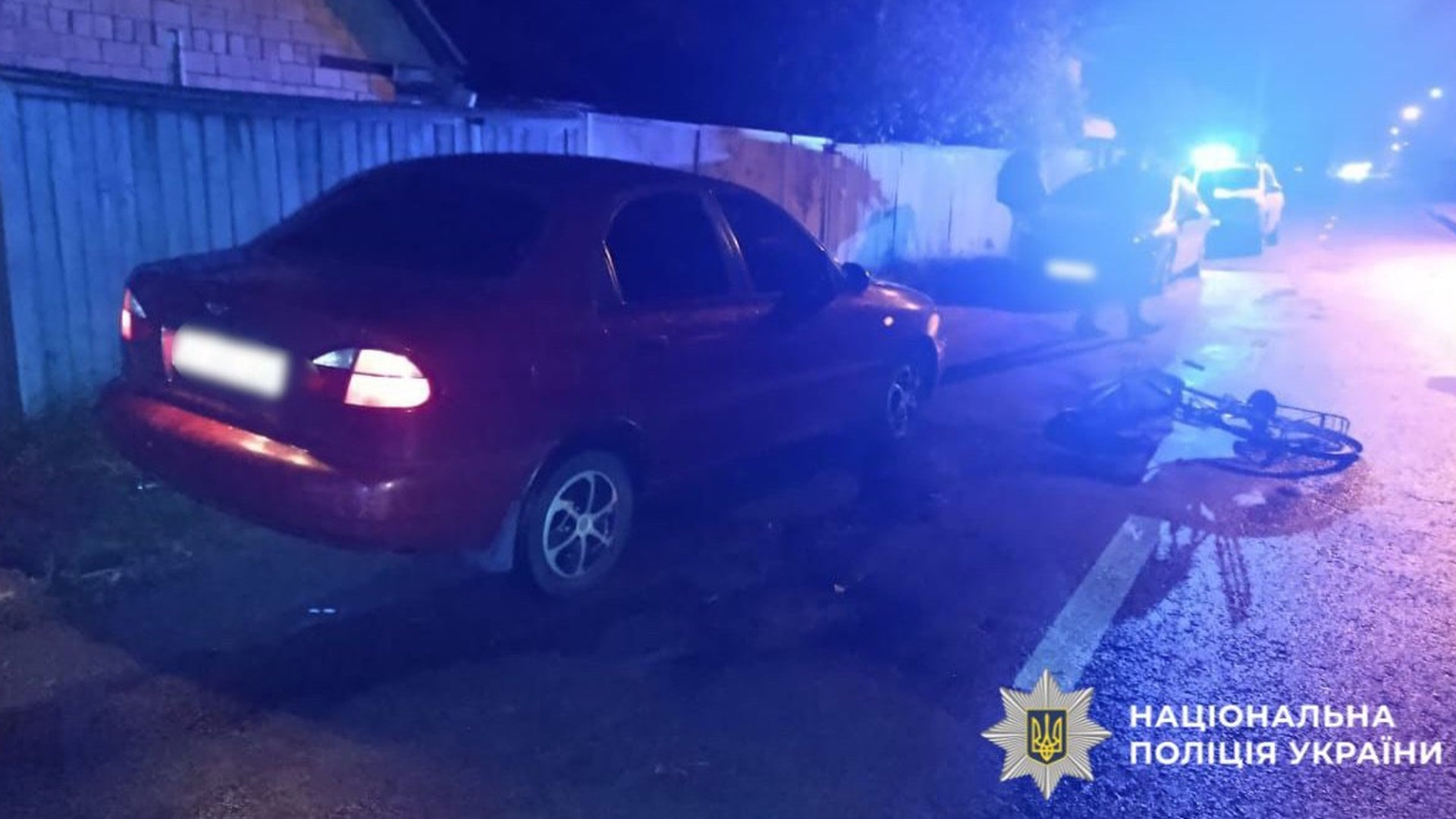 бордовий автомобіль марки Lanos в темноті на вулиці в ДТП з велосипедом, велосипед лежить на асфальті