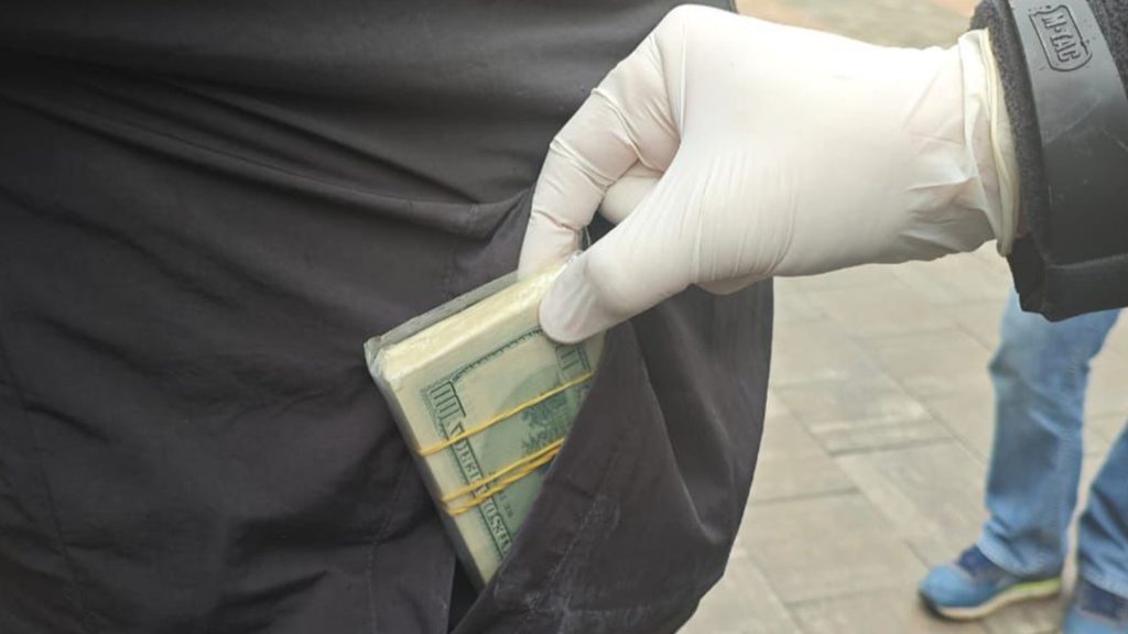 15 тисяч доларів за СЗЧ — у Києві затримали організатора схеми рука в білій рукавичці витягує доларові купюри з кишені