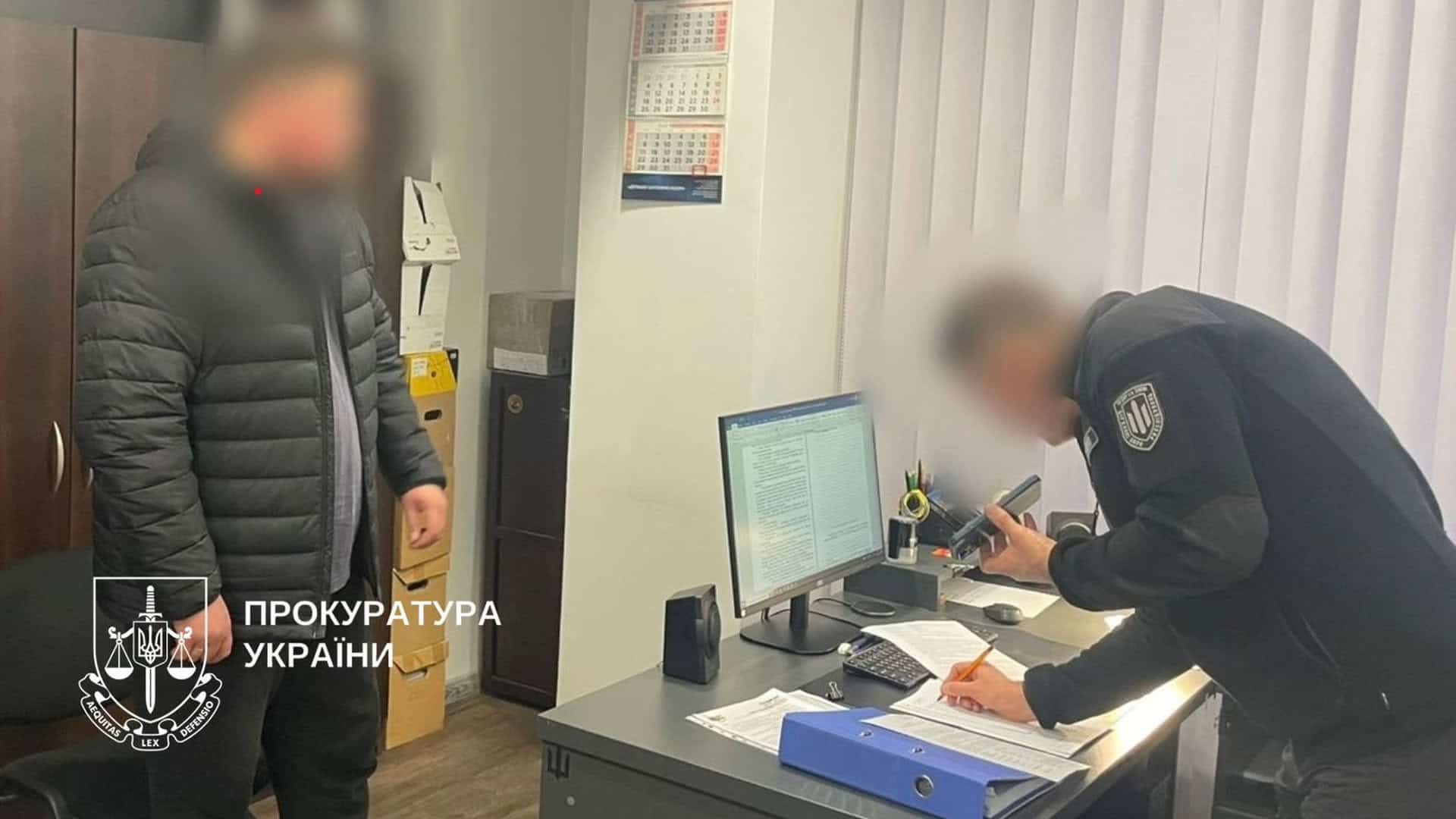 Працівник прокуратури стоїть у поліцейському відділку разом із підозрюваним, обидва чоловіки із заблюреними обличчями