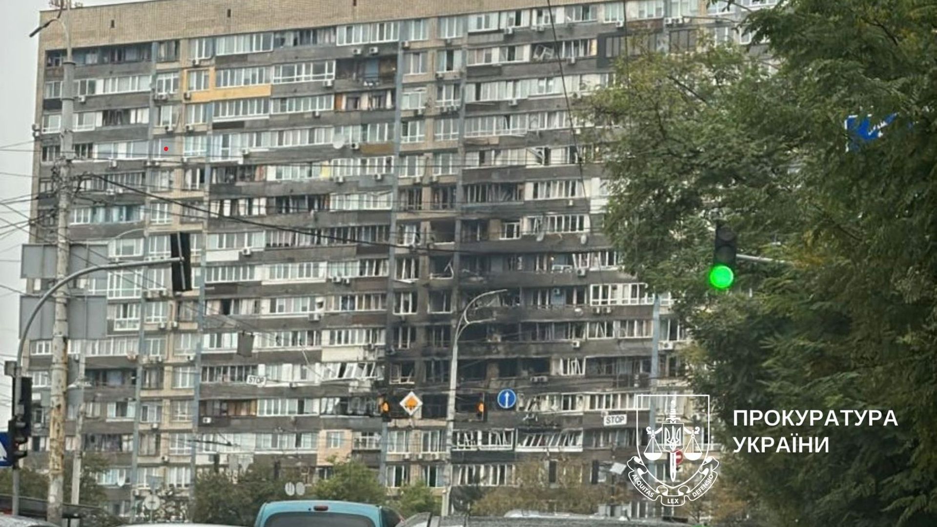 Багатоповерховий будинок із пошкодженнями від пожежі, знімок зроблено вдень біля світлофора з зеленим сигналом