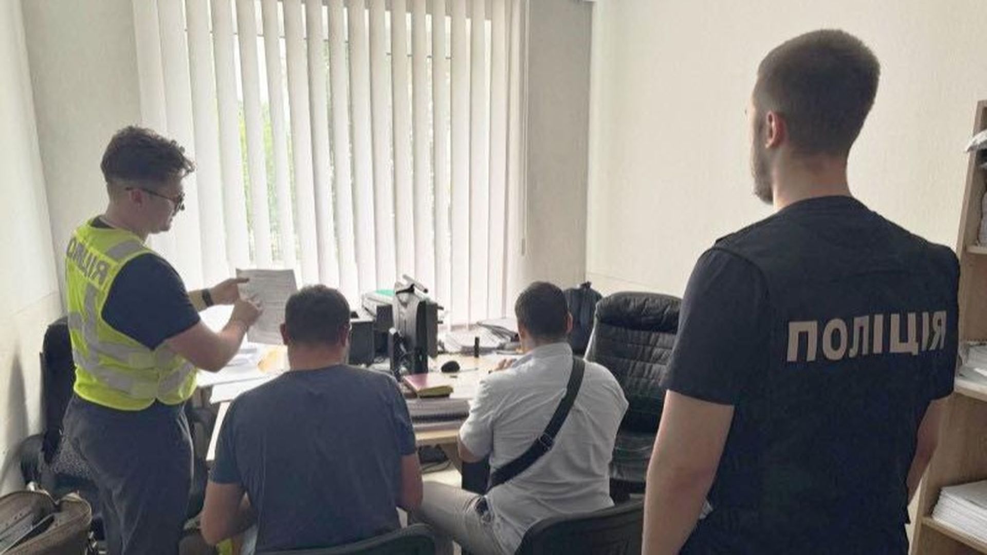 Кілька працівників поліції перевіряють та оформлюють документи в офісі