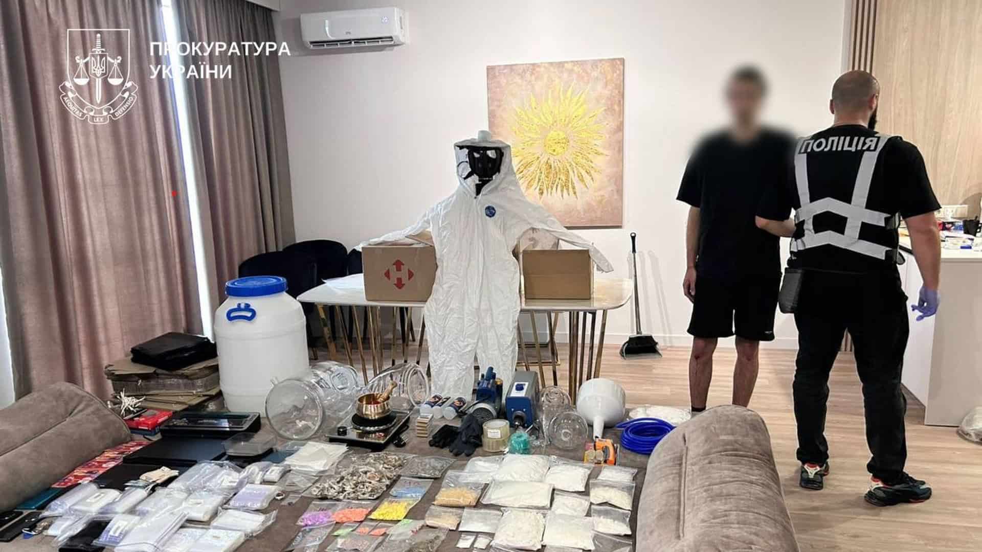 Поліція тримає затриманого, на дивані розкладені пакети з наркотиками