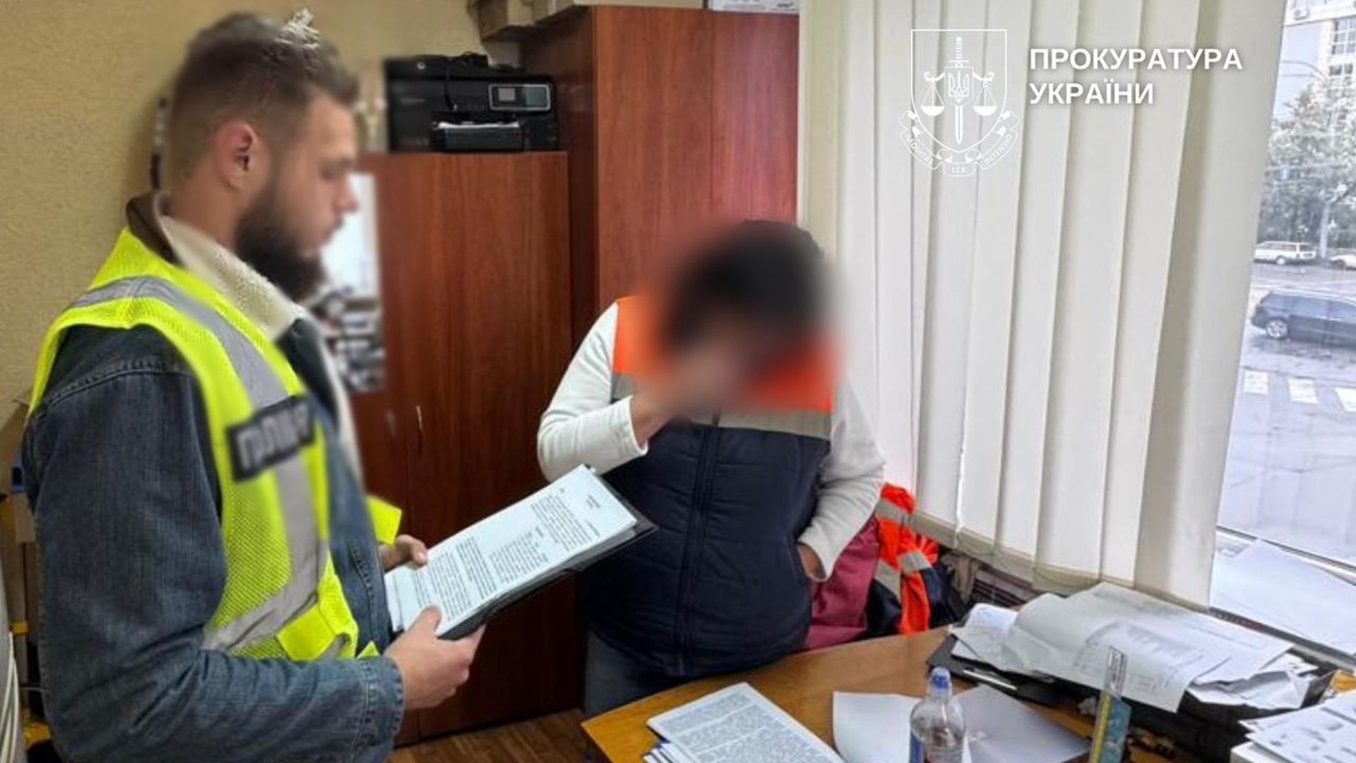 Поліцейський вручає документи посадовиці в офісі