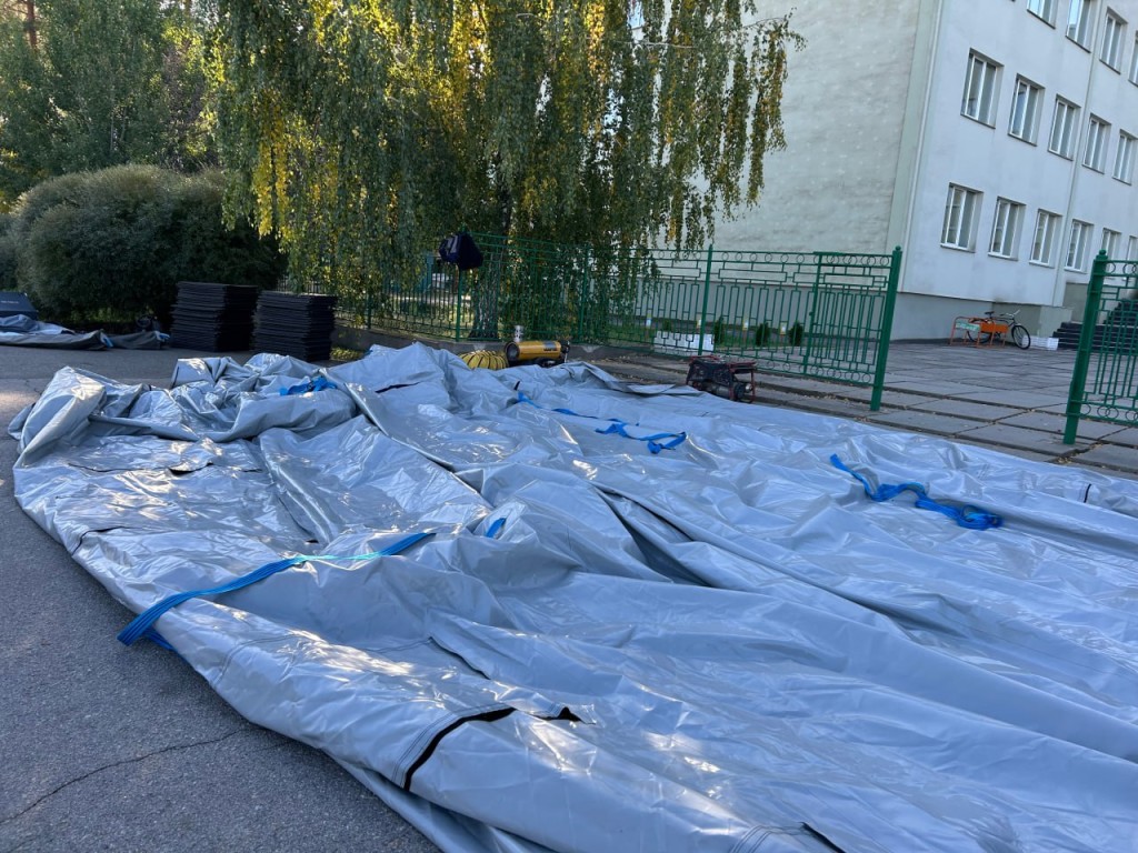 Біля будівлі у Славутичі працівники складають сірий намет після завершення роботи