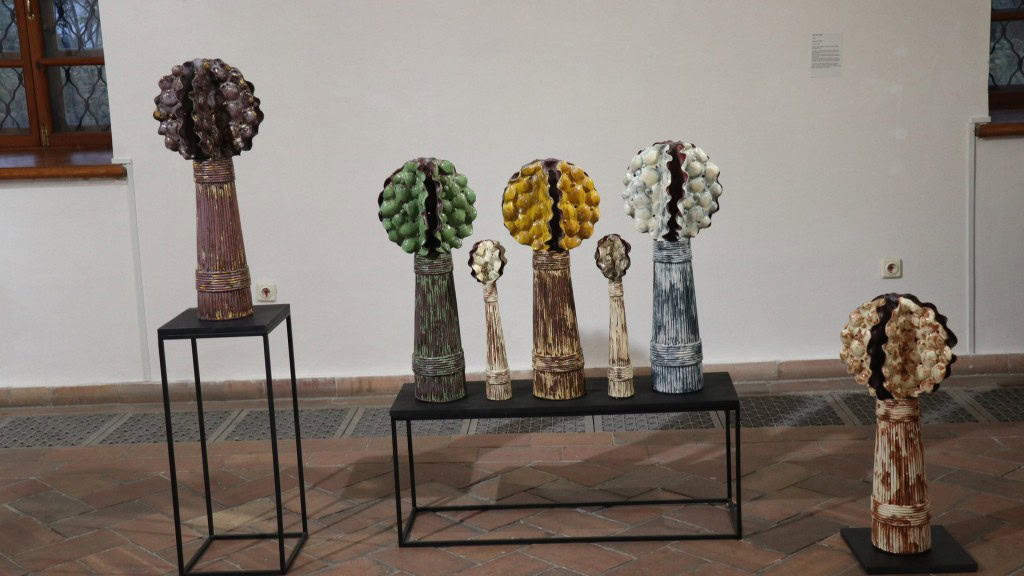 Глиняні скульптури стоять на столі на виставці Памʼять глини