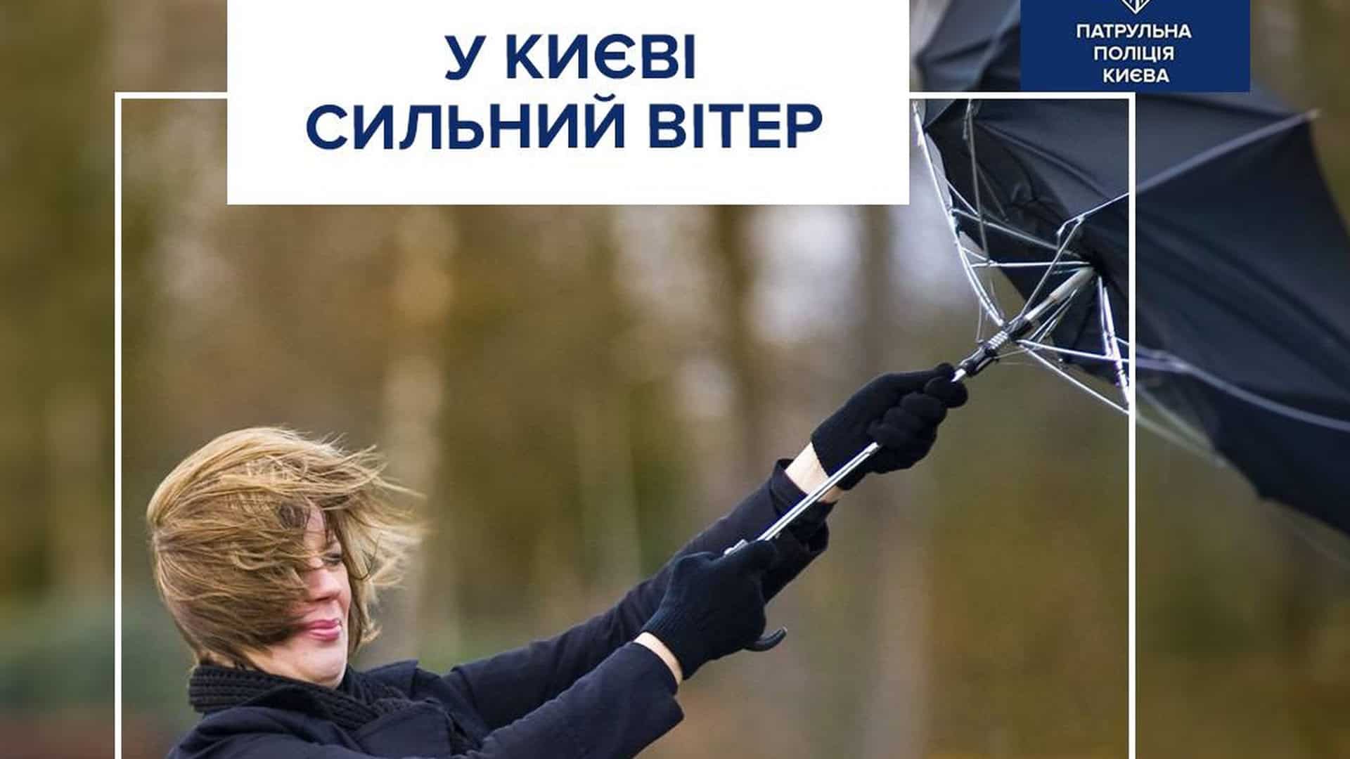 Дівчина тримає чорну парасолю, яку уносить вітром і вона аж вивернулась від цього