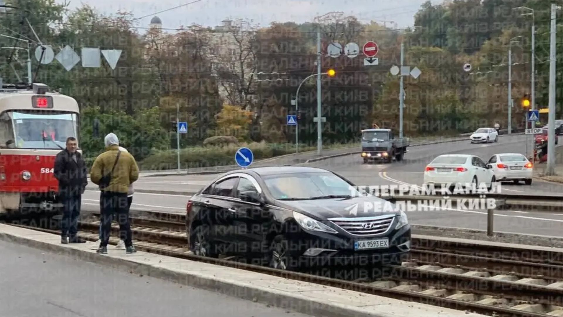 Чорний автомобіль Hyundai застряг на трамвайних коліях, поруч стоять люди та трамвай