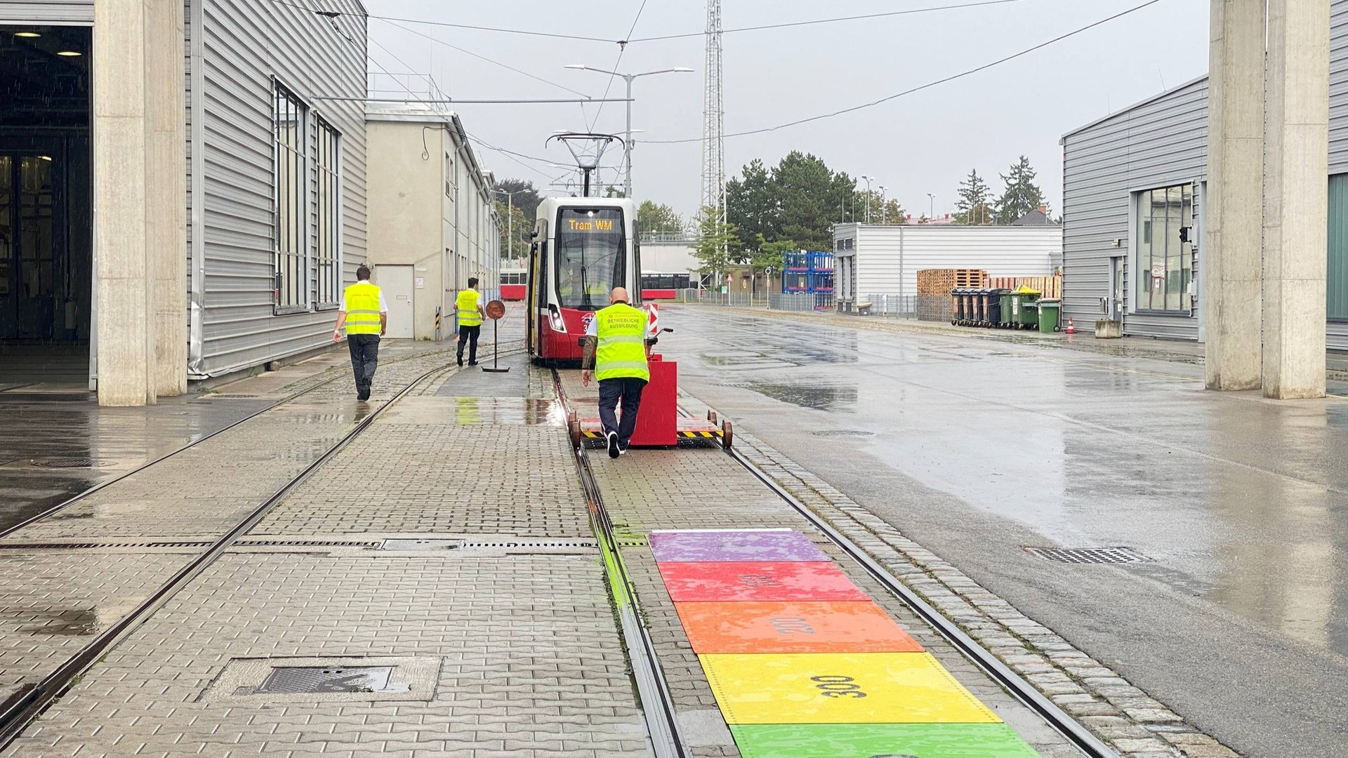 Трамвай стоїть на зупинці технічної станції обслуговування, біля нього кілька працівників трамвайного ДЕПО